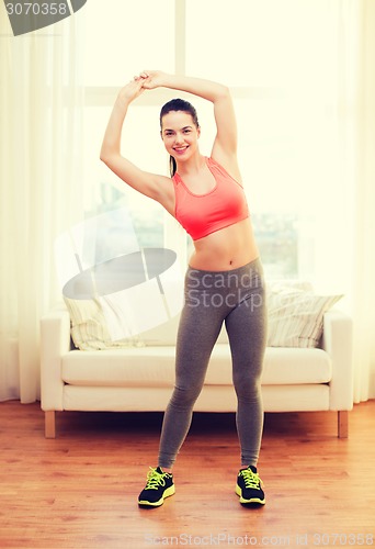 Image of smiling teenage girl streching at home