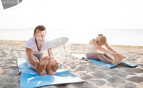 Image of couple making yoga exercises outdoors