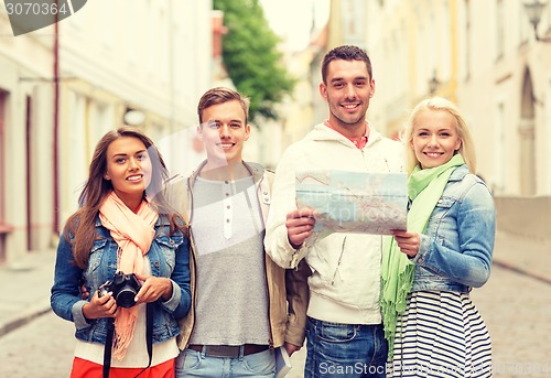 Image of group of smiling friends with map and photocamera