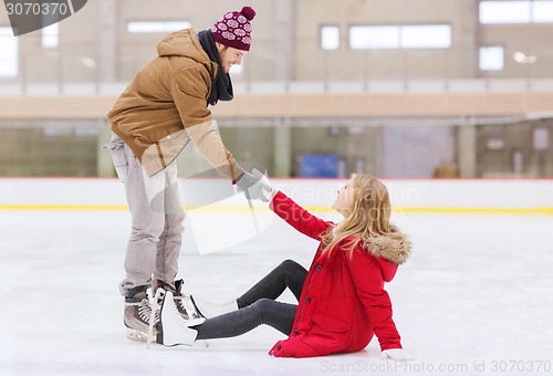 Image of man helping women to rise up on skating rink