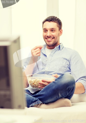 Image of smiling man watching sports at home