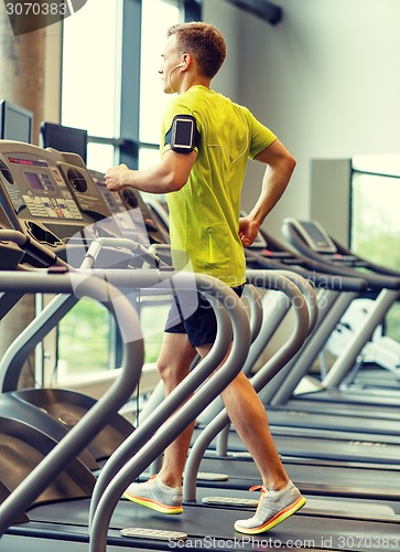 Image of man with smartphone exercising on treadmill in gym