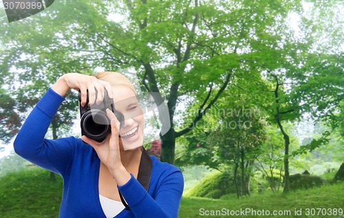 Image of smiling woman taking picture with digital camera