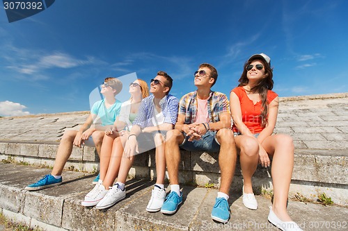 Image of group of smiling friends sitting on city street