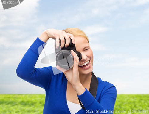 Image of smiling woman taking picture with digital camera