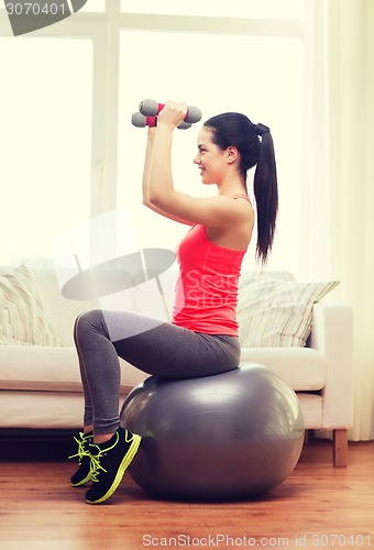 Image of smiling girl exercising with fitness ball