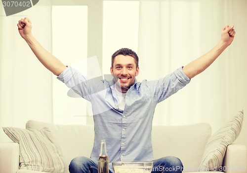 Image of smiling man watching sports at home