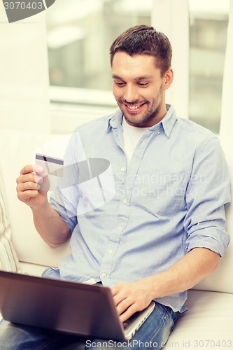 Image of smiling man working with laptop and credit card