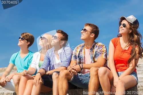 Image of group of smiling friends sitting on city street