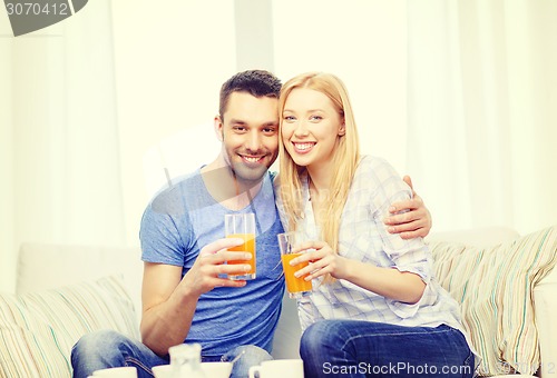 Image of smiling happy couple at home drinking juice