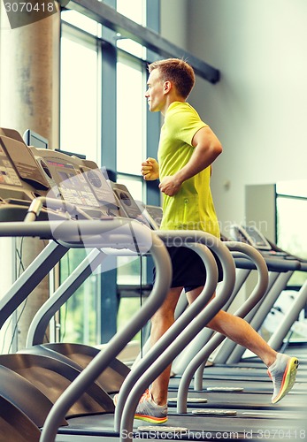 Image of smiling man exercising on treadmill in gym