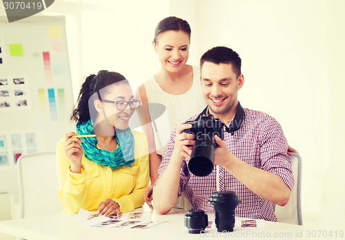 Image of smiling team with photocamera working in office