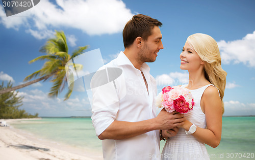 Image of happy couple with flowers over beach background