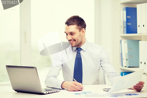 Image of smiling businessman with laptop and documents