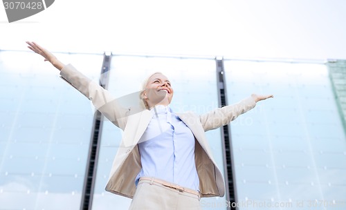 Image of young smiling businesswoman over office building