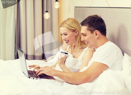 Image of couple in bed with laptop computer and credit card