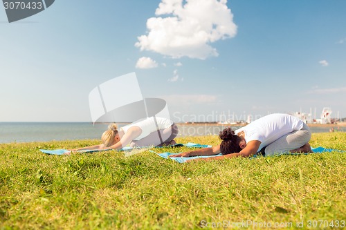 Image of couple making yoga exercises outdoors