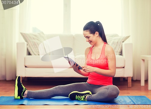 Image of smiling teenage girl streching on floor at home