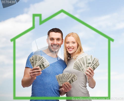 Image of smiling couple holding money over green house