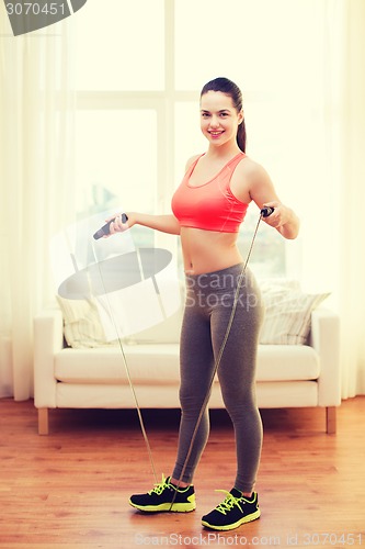 Image of smiling teenage girl with skipping rope at home