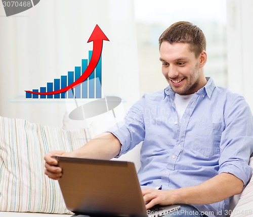 Image of smiling man with laptop and growth chart at home