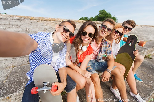 Image of group of smiling friends with smartphone outdoors