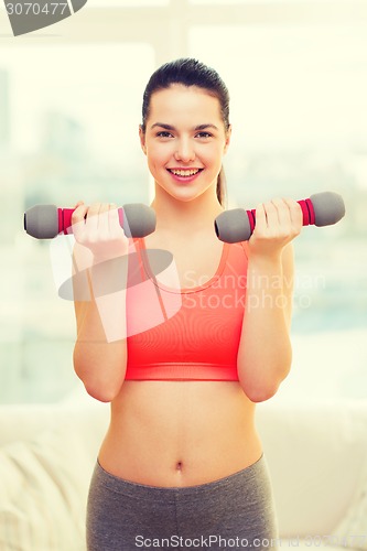 Image of smiling teenage girl exercising with dumbbells