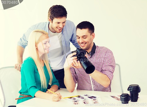 Image of smiling team with photocamera working in office