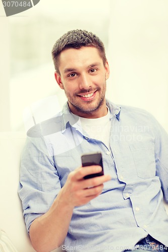 Image of smiling man with smartphone at home