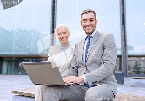 Image of smiling businesspeople with laptop outdoors