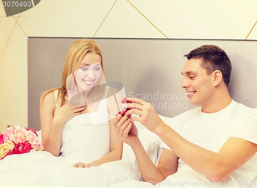 Image of man giving woman little red box and ring in it