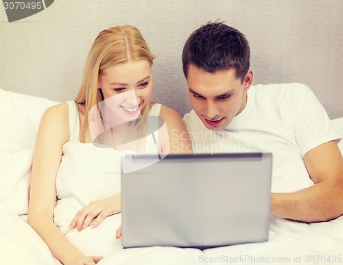 Image of smiling couple in bed with laptop computer