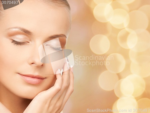 Image of beautiful young woman touching her face