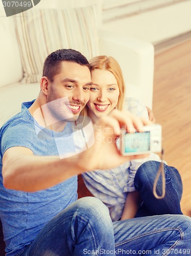 Image of smiling couple taking picture with digital camera