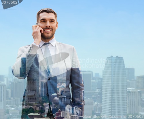 Image of smiling businessman with smartphone in city