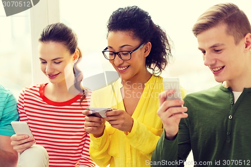 Image of three smiling students with smartphone at school