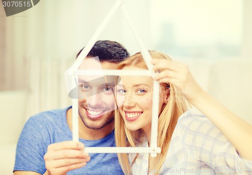 Image of smiling couple with house from measuring tape