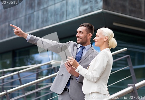 Image of smiling businessmen with tablet pc outdoors