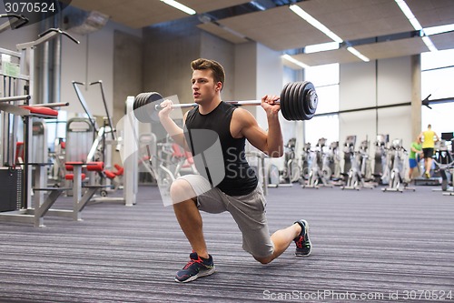 Image of young man flexing muscles with barbell in gym