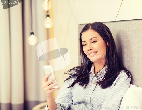 Image of happy businesswoman with smartphone in hotel room