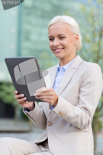 Image of smiling businesswoman with tablet pc outdoors