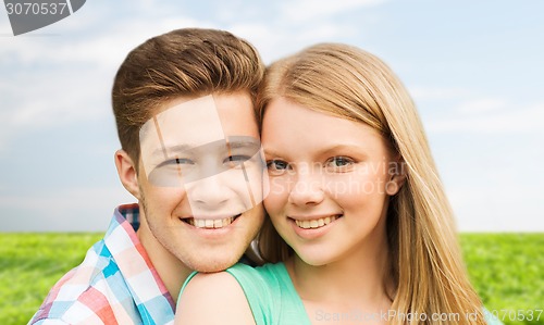 Image of smiling couple hugging over natural background