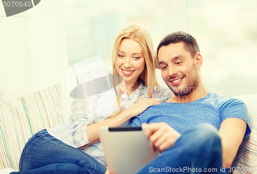 Image of smiling happy couple with tablet pc at home