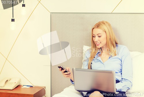 Image of happy businesswoman with smartphone in hotel room