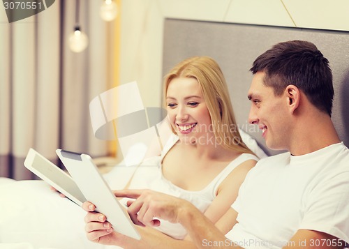 Image of smiling couple in bed with tablet pc computers