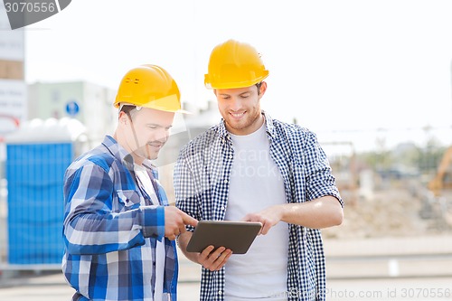 Image of smiling builders in hardhats with tablet pc