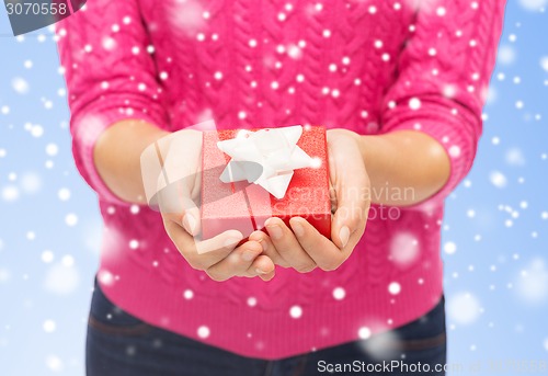 Image of close up of woman in pink sweater holding gift box