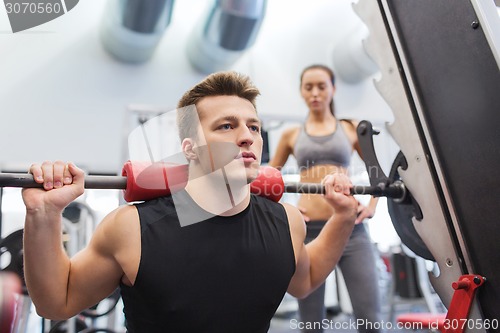 Image of man and woman with barbell flexing muscles in gym