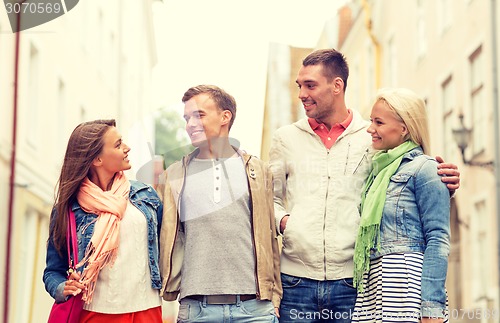 Image of group of smiling friends walking in the city