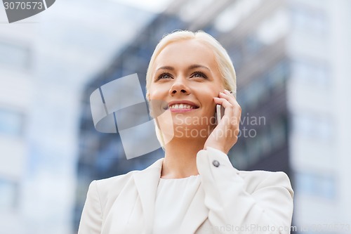 Image of smiling businesswoman with smartphone outdoors